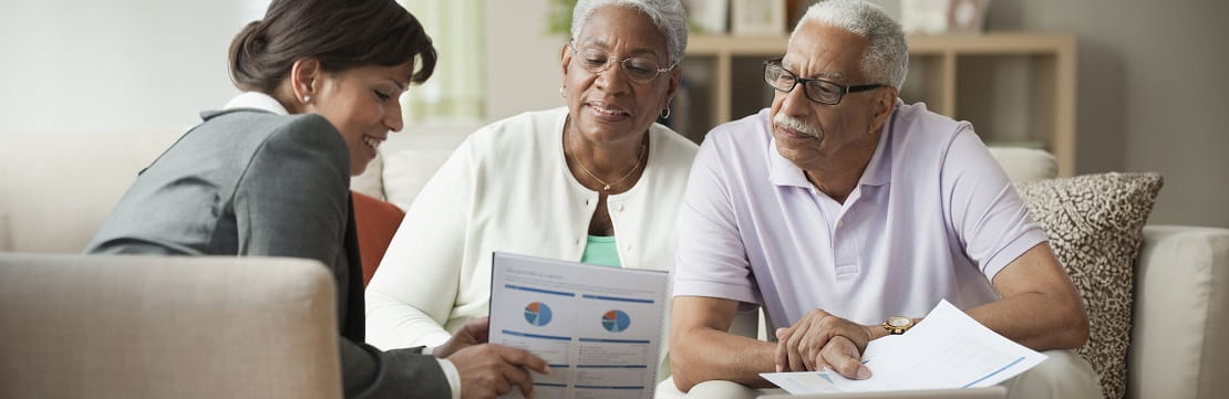 Senior couple reviewing financial documents with a professional. 